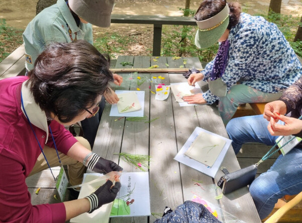 ‘야외치유 프로그램’ 참가자들이 매봉산 치유의 숲에서 만들기 체험을 하고 있다. [사진=마포구치매안심센터]