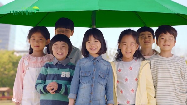 초록우산을 쓰고 웃고 있는 아동들. [사진=초록우산 어린이재단]