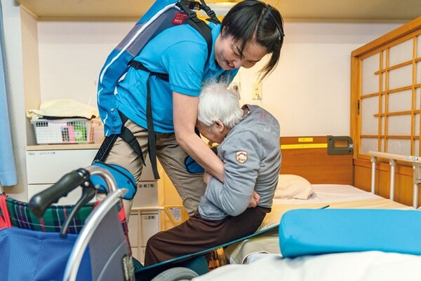 외골격 슈트를 입고 어르신을 이동시키고 있는 일본의 개호사 (사진=일본 정부)
